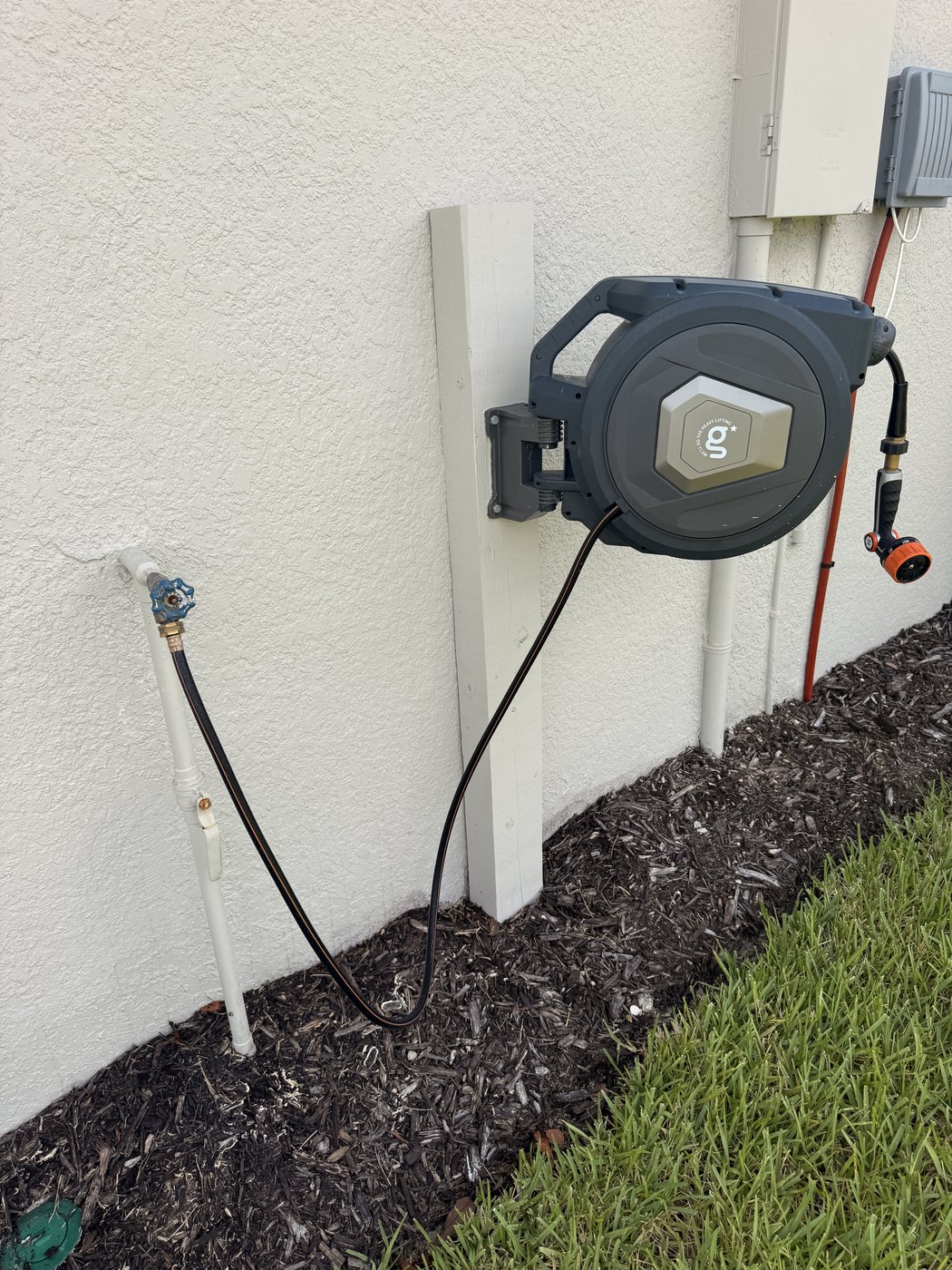 Retractable hose reel installation on exterior wall in Sarasota FL