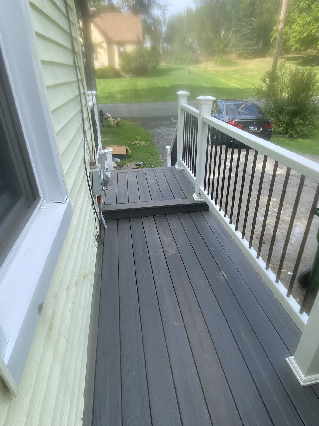 Composite deck construction with white railings, view toward driveway